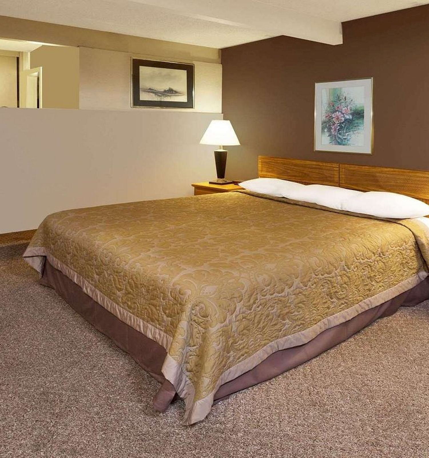 The image shows a bedroom with a large bed, two nightstands with lamps, paintings on the wall, and a carpeted floor.